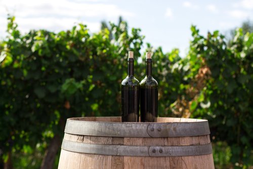 Two bottles atop a wooden barrel