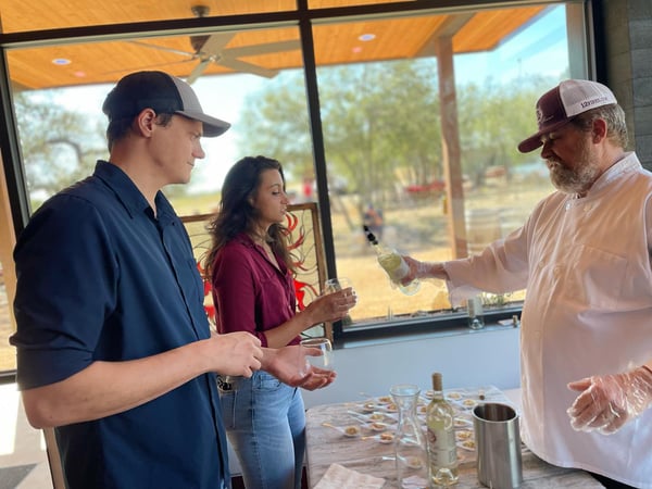 Two glampers sampling wine poured by wine expert